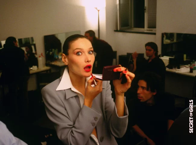Carla Bruni, ultra smooth bun and glamorous red mouth, backstage at Fashion Week in 1994 | Carla Bruni: Her Beauty Evolution In 50 Looks