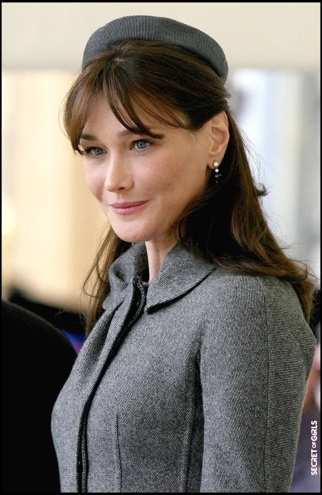 Carla Bruni with tapered bangs, and wearing a mouse gray fascinator, in Windsor in 2008 | Carla Bruni: Her Beauty Evolution In 50 Looks