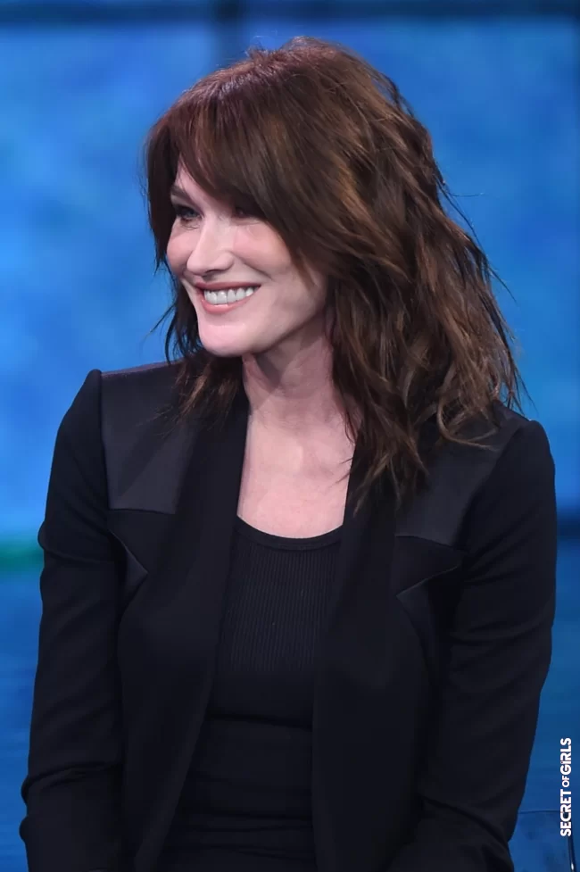 Carla Bruni and her dark brown wavy hair, on the set of a show in Italy, February 3, 2018 | Carla Bruni: Her Beauty Evolution In 50 Looks